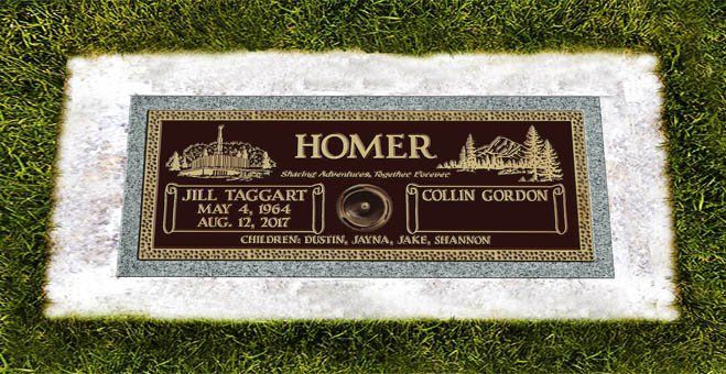 Bronze memorial plaque on grass reading “HOMER,” with decorative borders and two name panels.
