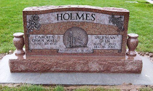 Granite gravestone engraved HOLMES with decorative urns in a grassy cemetery.
