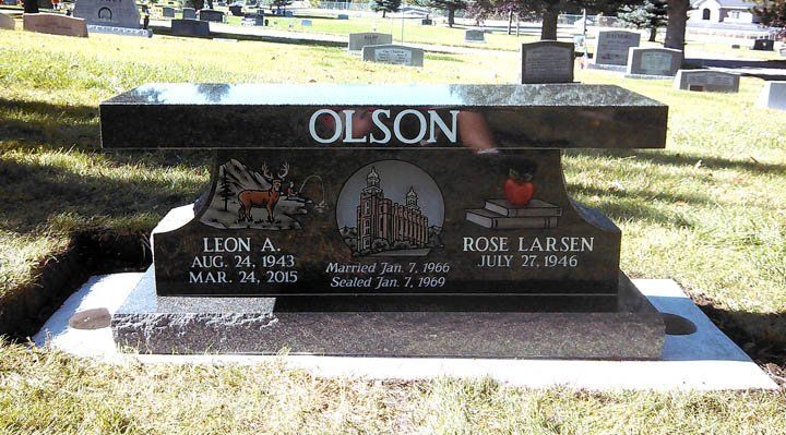 Gravestone with the name OLSON in a cemetery, featuring two memorial plaques on a black bench-style monument