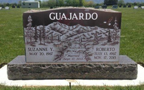 Gujardo family gravestone in a grassy cemetery, with names Suzanne Y. and Roberto on a dark stone marker