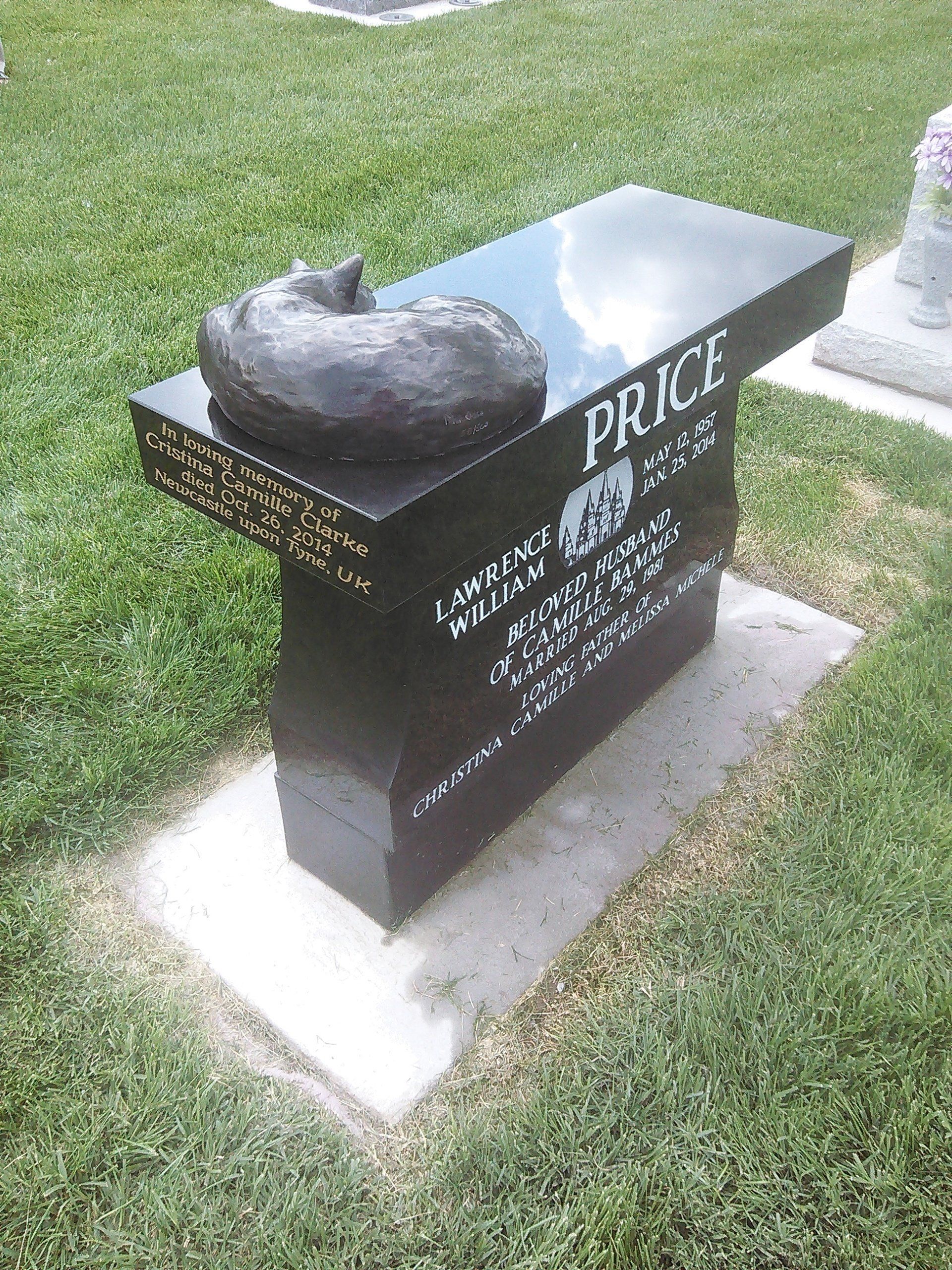 Black granite memorial bench with engraved name and a small cat statue, set on a grassy lawn.