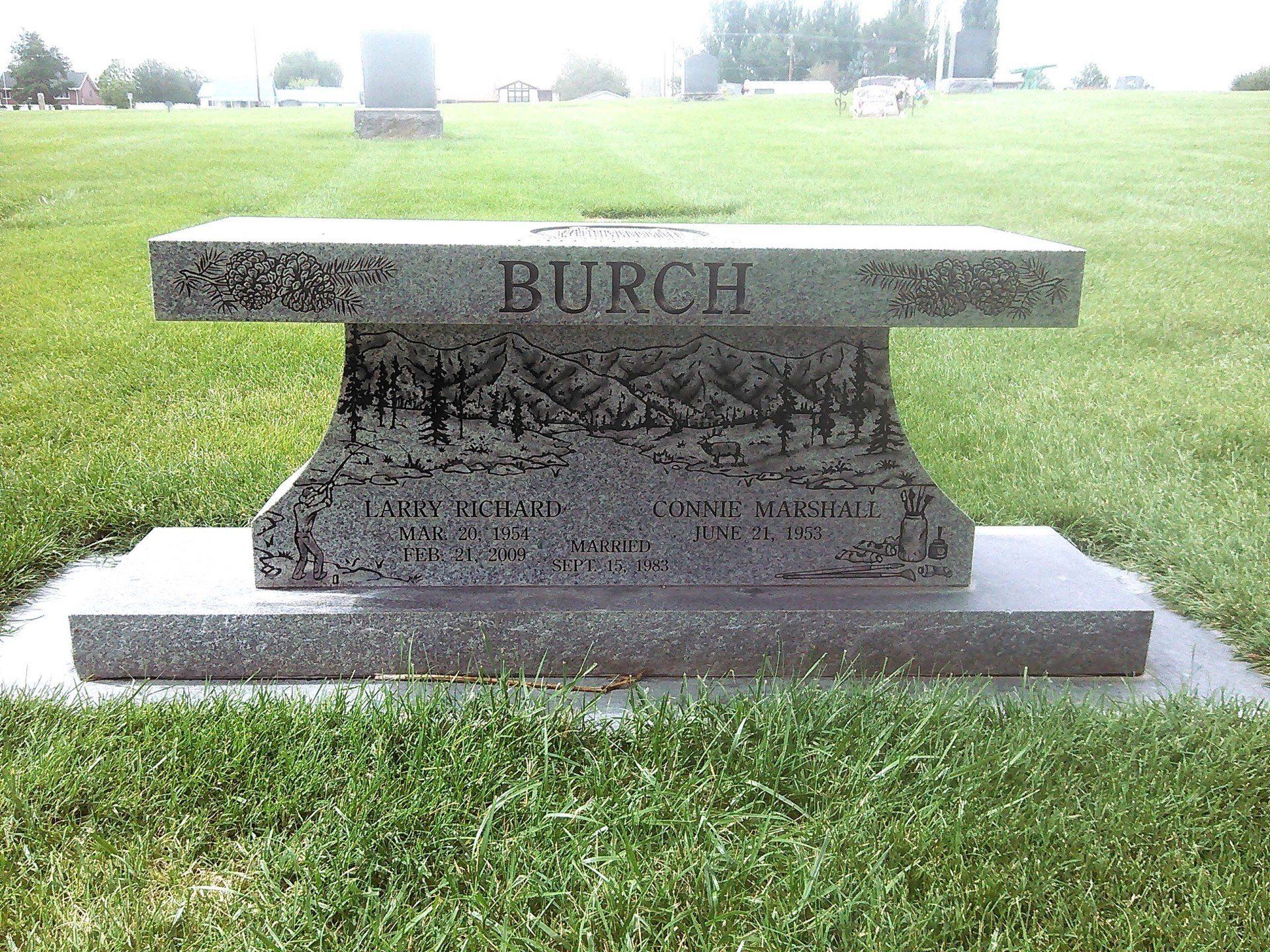 Granite cemetery bench headstone engraved “BURCH” in a grassy memorial cemetery.