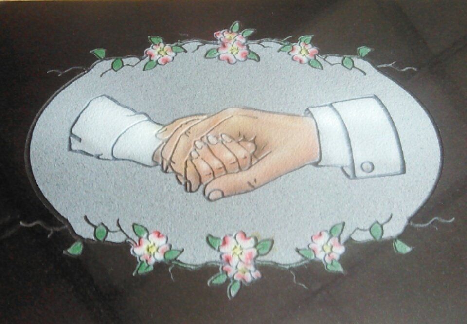 Two hands clasped in a handshake, framed by pink flowers on a gray oval background.