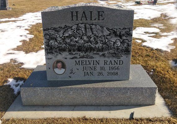 Gray gravestone in a snowy cemetery engraved with “HALE” and “Melvin Rand.”
