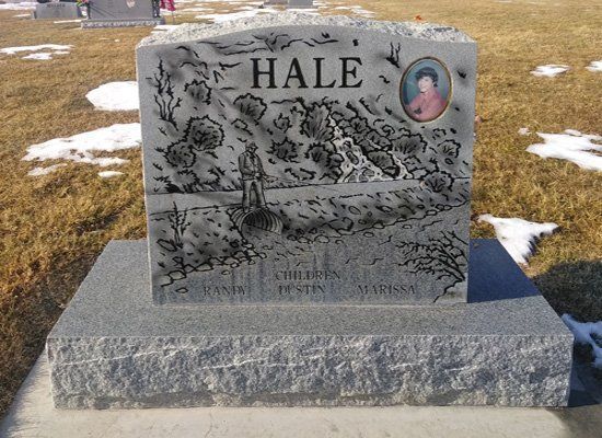 Gray memorial headstone engraved “HALE” in a snowy cemetery, with a small portrait medallion.