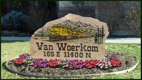 Van Woerkom neighborhood stone sign with pink flowers and trees in the background