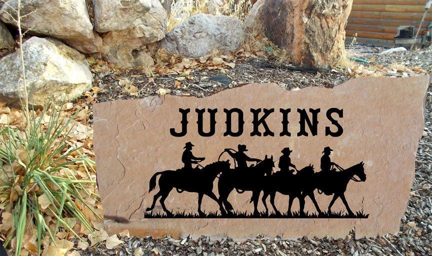 Stone sign reading “JUDKINS” with black cattle silhouettes in a desert rock setting