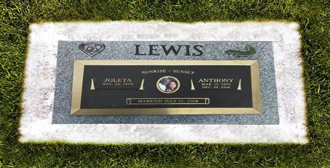 Memorial plaque for Lewis set in a stone marker on grass, with a black and gold nameplate.