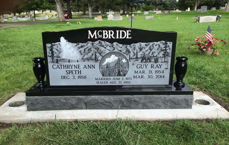 Black McBride gravestone in a cemetery with engraved portraits and American flags on the right