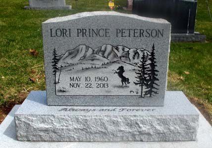 Gray granite gravestone for Lori Prince Peterson with mountain and skier engraving in a grassy cemetery