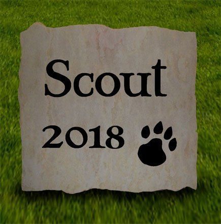 Stone plaque reading “Scout 2018” with a black paw print on grass