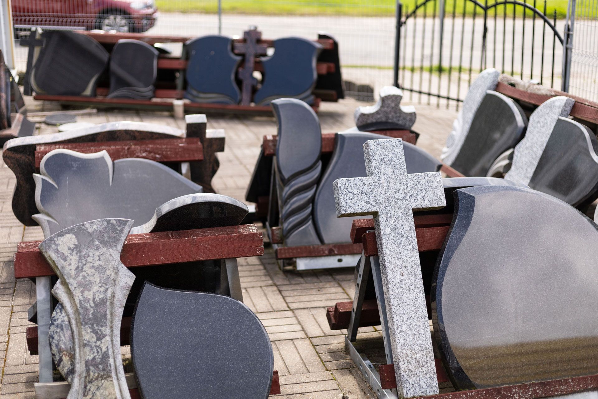 Rows of gray and black gravestones in a cemetery, including a prominent white cross tombstone.