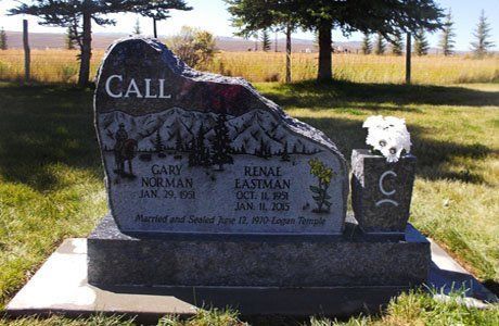 Headstone memorial with “CALL” engraved, beside a smaller black marker in a grassy cemetery.