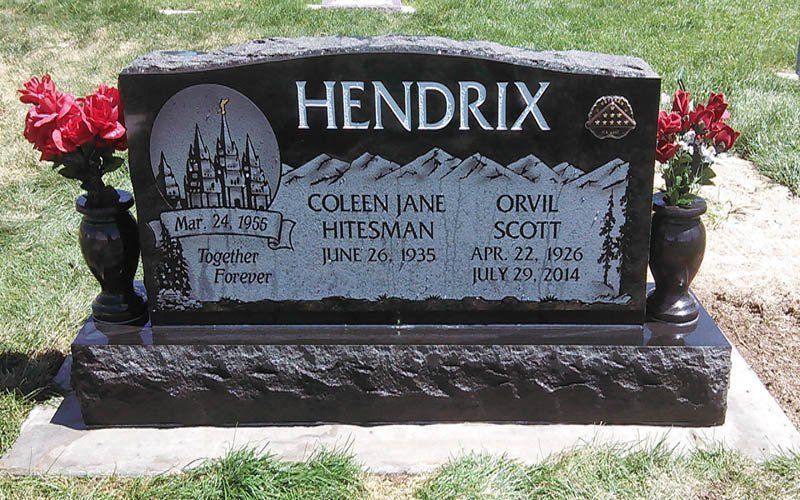 Black headstone engraved HENDRIX with flowers beside it in a cemetery