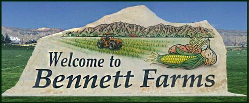 Welcome to Bennett Farms sign in a field with mountains and blue sky
