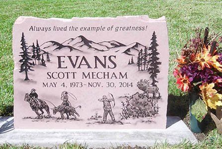 Pink engraved gravestone for Scott Mecham with flowers beside it in a cemetery.