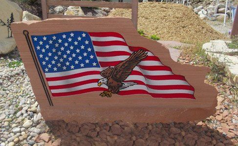 Wavy American flag painted on a stone monument with a hawk in the center.