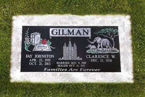Gilman family gravestone with white lettering and engraved scenes in a grassy cemetery