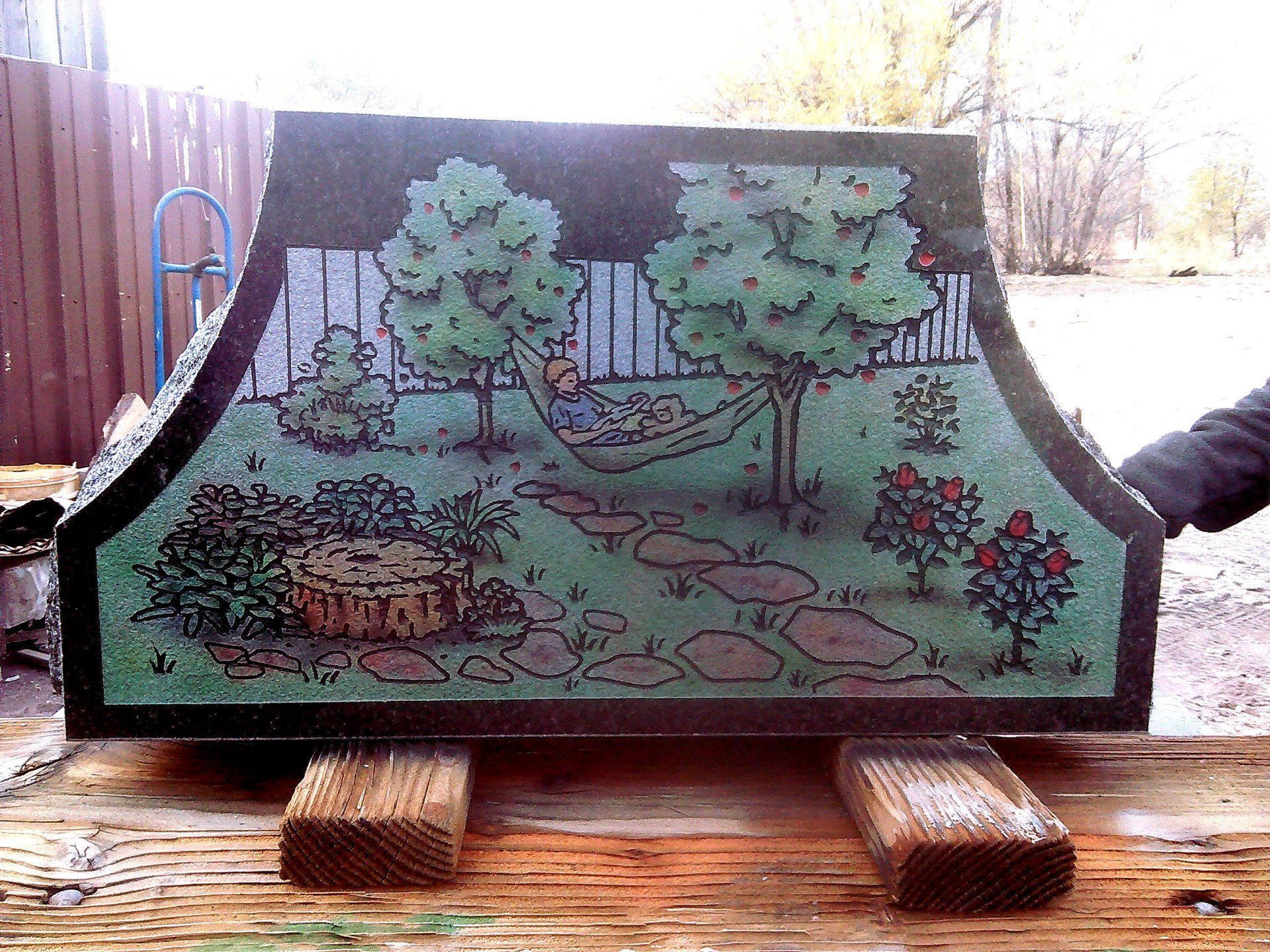 Green-painted wooden chest with a garden scene and birds, sitting on wooden blocks outdoors