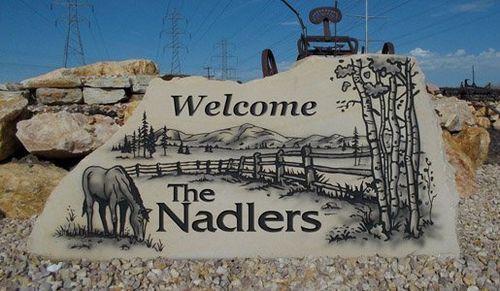 Welcome sign for The Nadlers, painted on a stone slab with desert rocks and a donkey illustration.