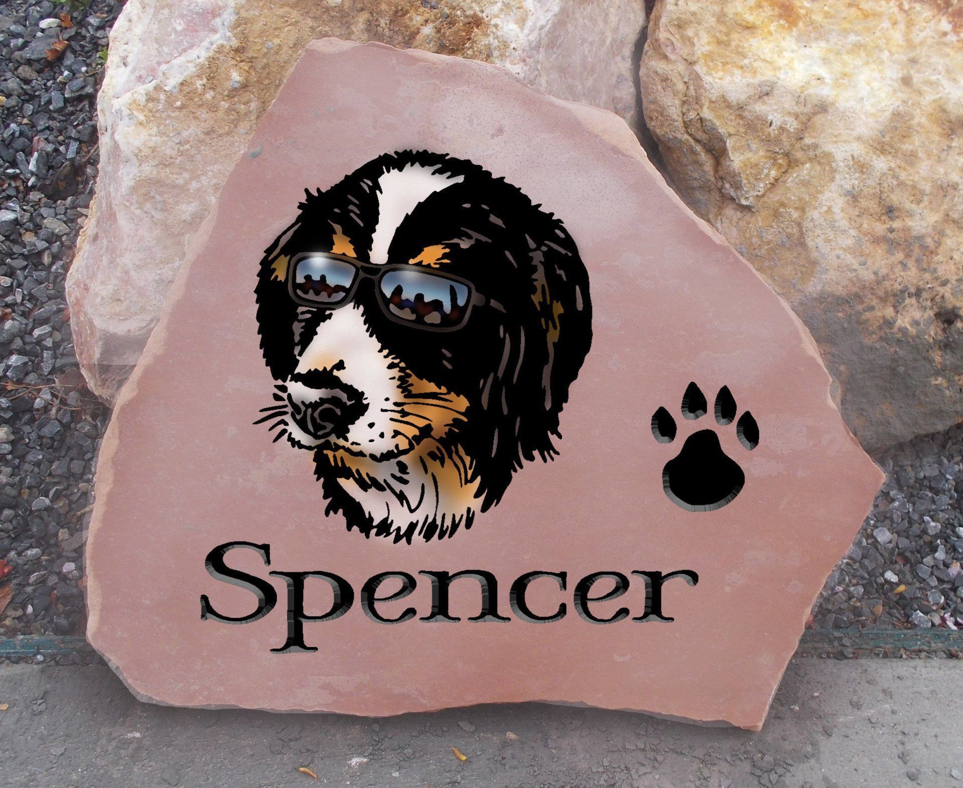 Pink memorial stone engraved with a black-and-white dog wearing sunglasses, paw print, and the name Spencer