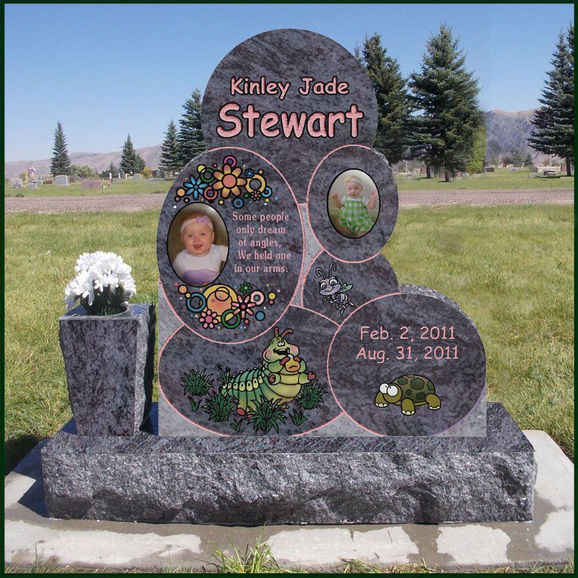 Child memorial headstone with photos, floral etching, and dates in a grassy cemetery.