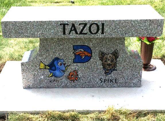 Gray granite pet memorial bench engraved “TAZOI” with colorful cartoon and dog images outdoors