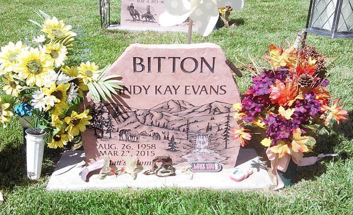 Bitton memorial headstone with floral tributes on both sides in a grassy cemetery