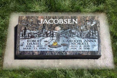 Jacobsen family gravestone in grass, engraved with two portraits and names Robert and Carolyn Anna.