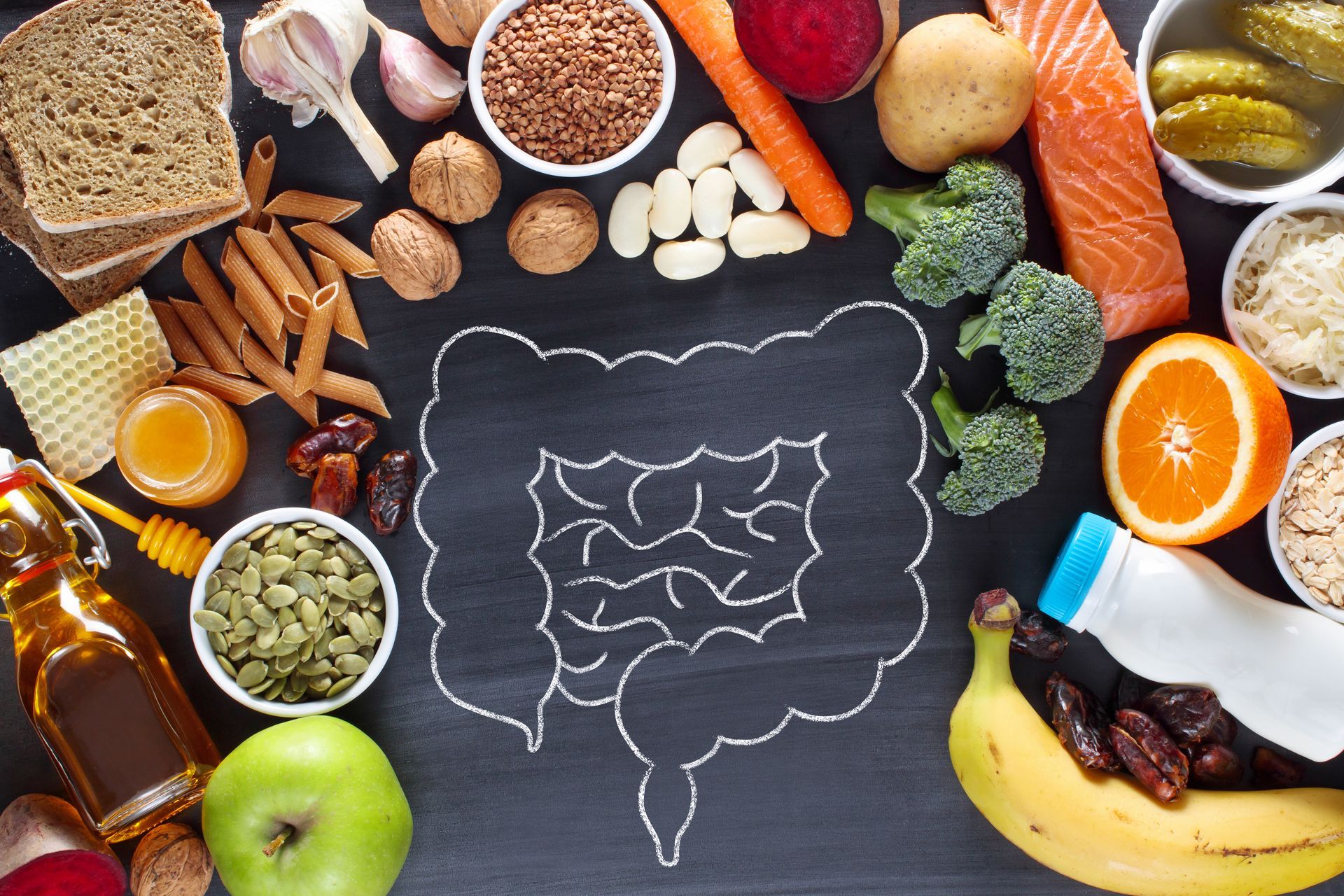 Chalk drawing of stomach and colon surrounding by healthy foods.