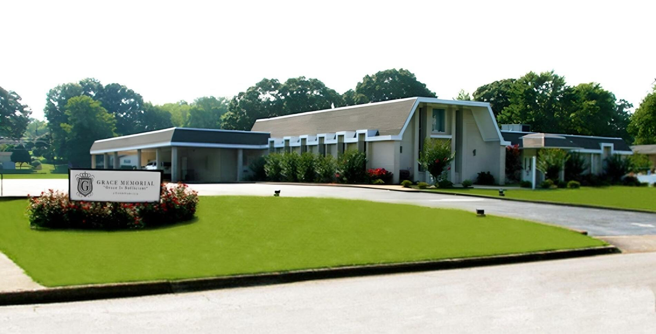 Single-story white building with a lawn and sign in front on a sunny day
