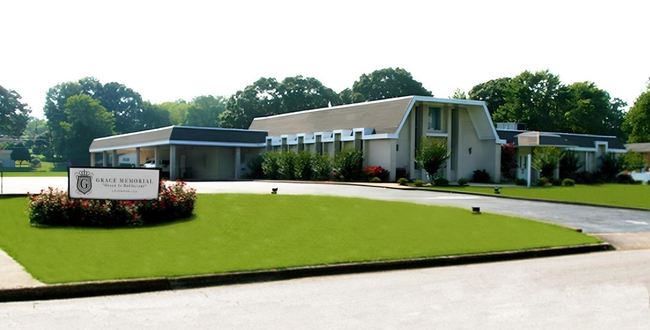 Single-story white building with a lawn and sign in front on a sunny day