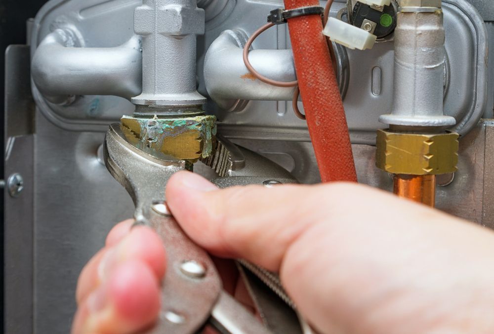 A Person Is Fixing A Boiler With A Wrench — Bennett Plumbing In Broughton Village, NSW