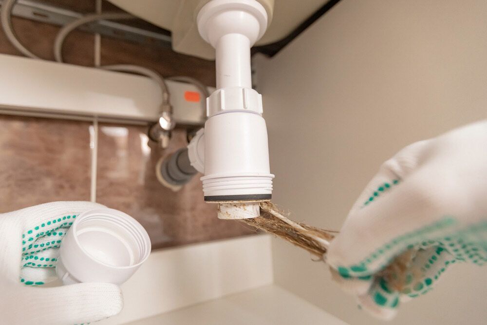 A Person Is Fixing A Sink Pipe With A Wrench — Bennett Plumbing In Broughton Village, NSW