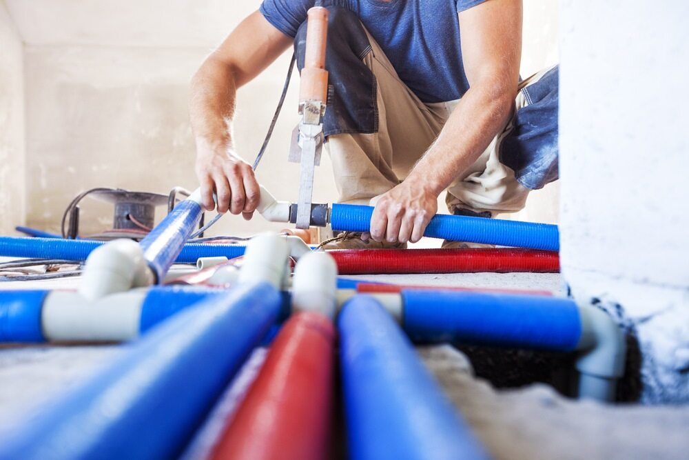A Man Is Working On A Pipe System In A Room — Bennett Plumbing In Broughton Village, NSW