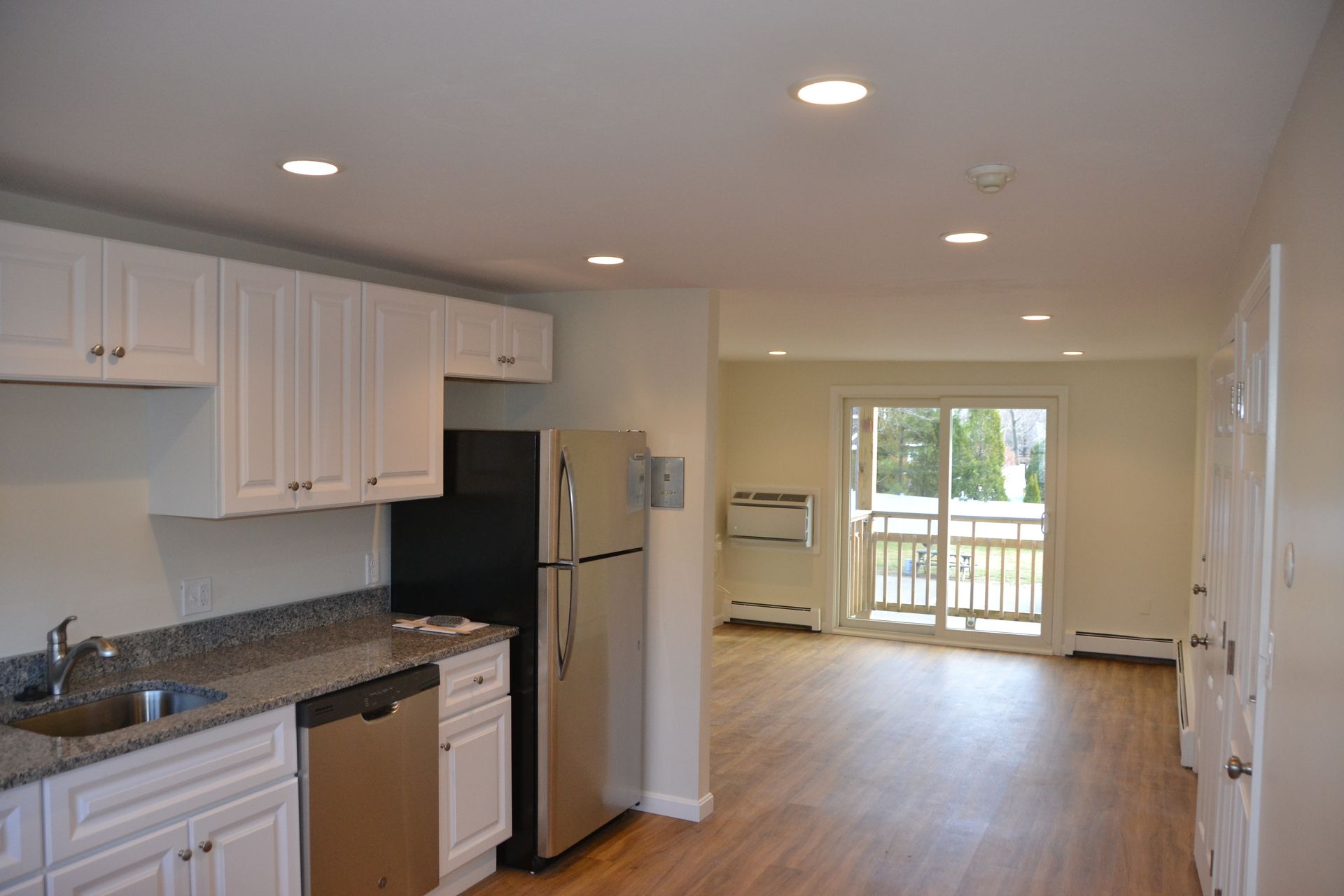 An empty kitchen with white cabinets and a black refrigerator.
