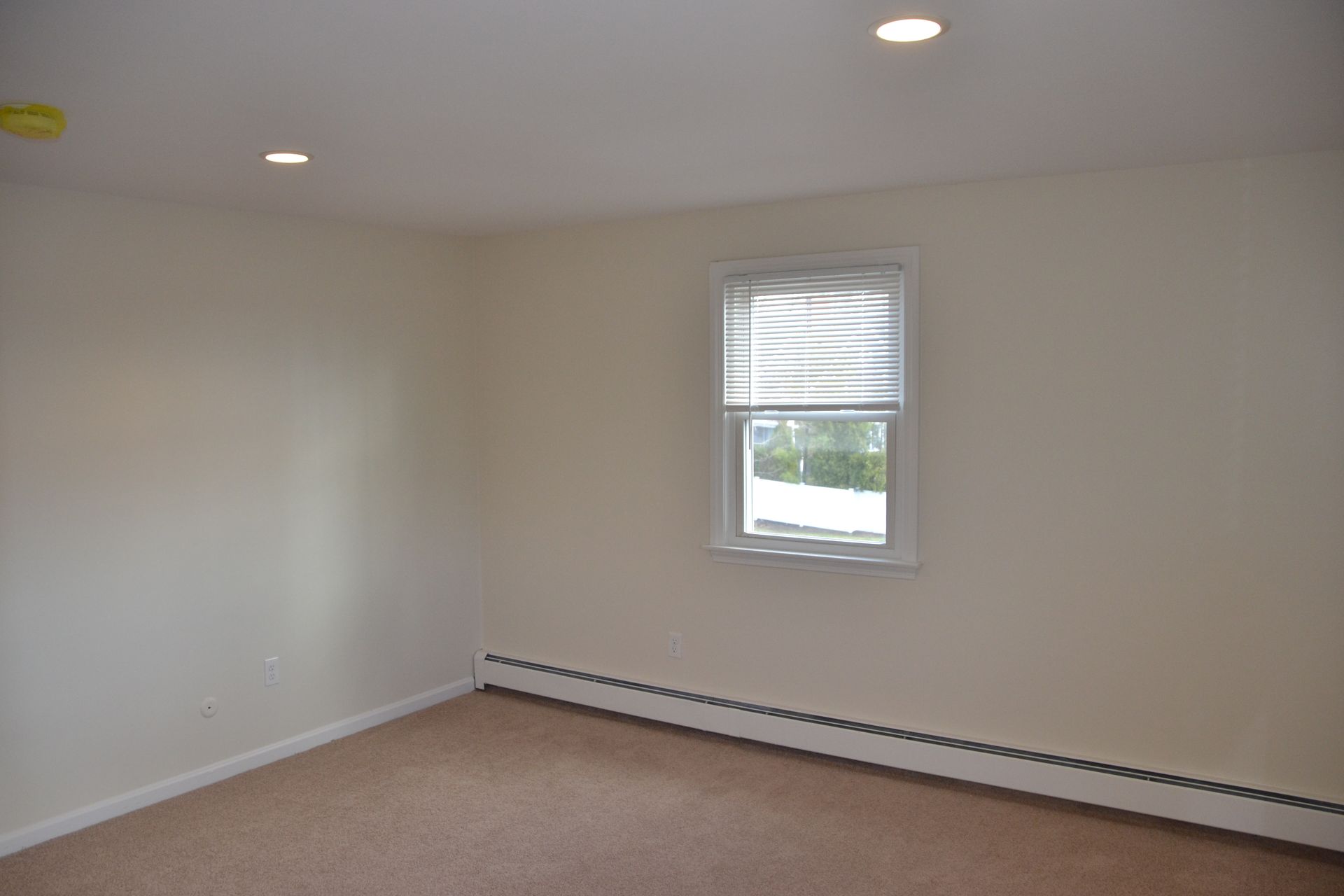 An empty room with a window and a carpeted floor
