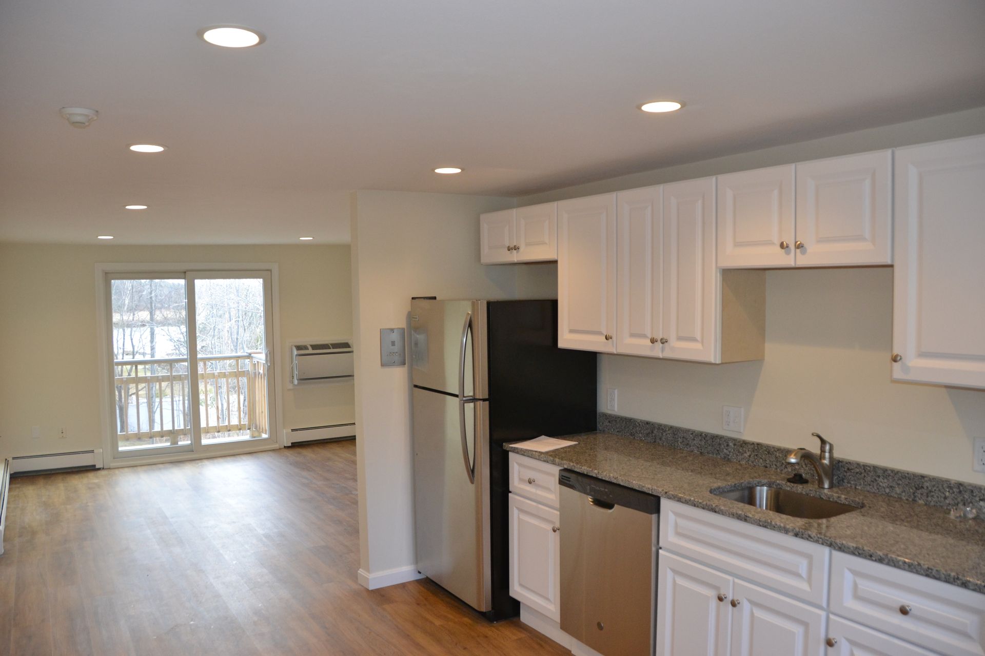 A kitchen with white cabinets , stainless steel appliances , a refrigerator and a sink.