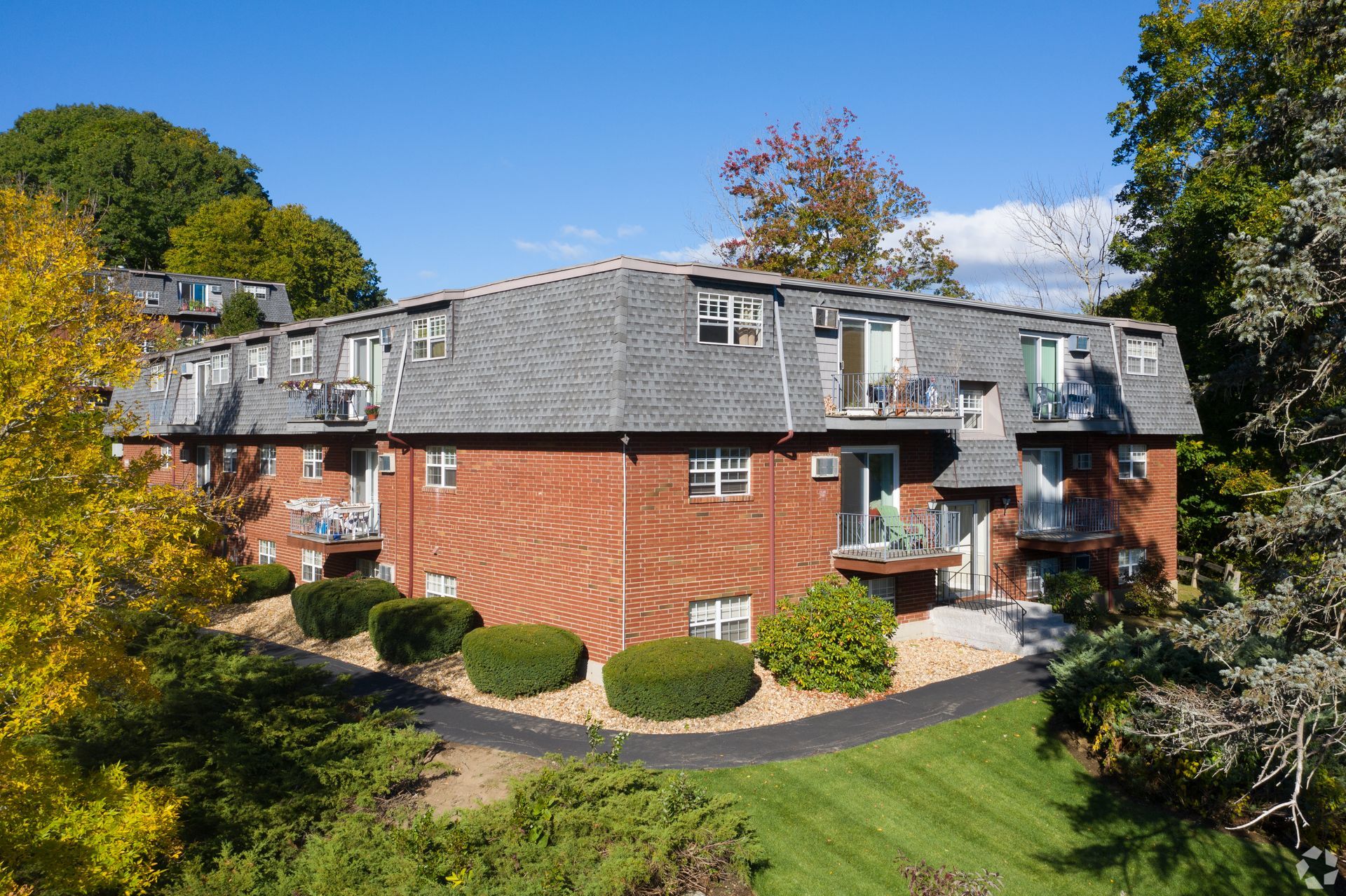 An aerial view of a brick apartment building surrounded by trees