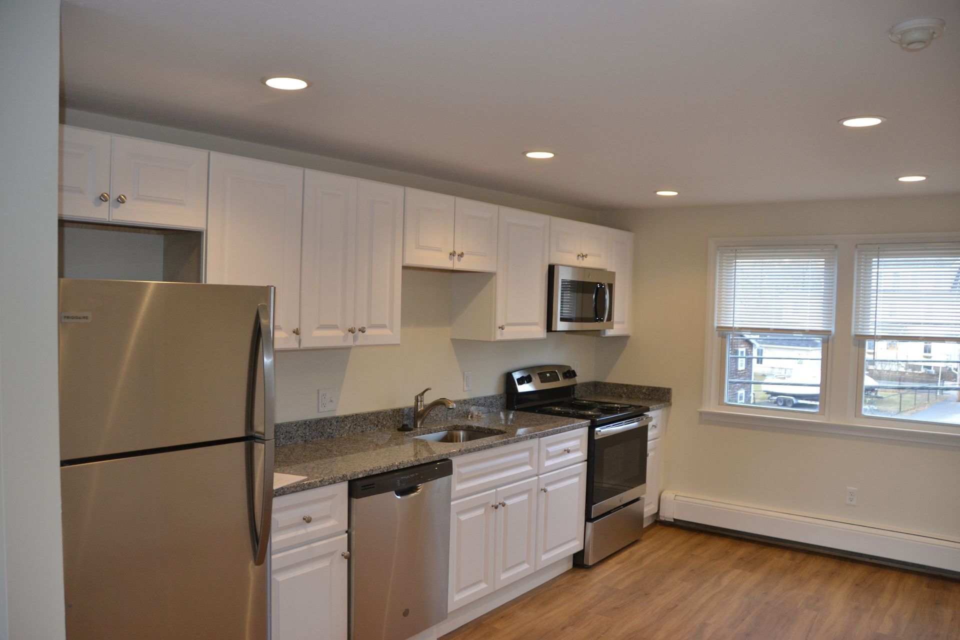 A kitchen with white cabinets , stainless steel appliances , and a refrigerator.
