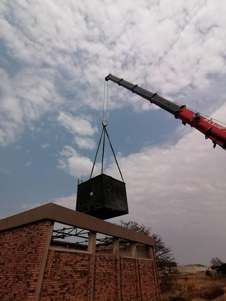 A Crane Is Lifting A Large Black Box On Top Of A Brick Building — All Lift Cranes In Nowra, NSW