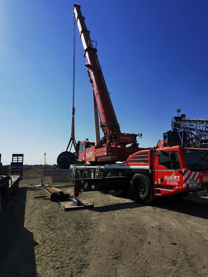 A Large Red Crane Is Sitting On Top Of A Truck In A Dirt Field — All Lift Cranes In St Georges Basin, NSW