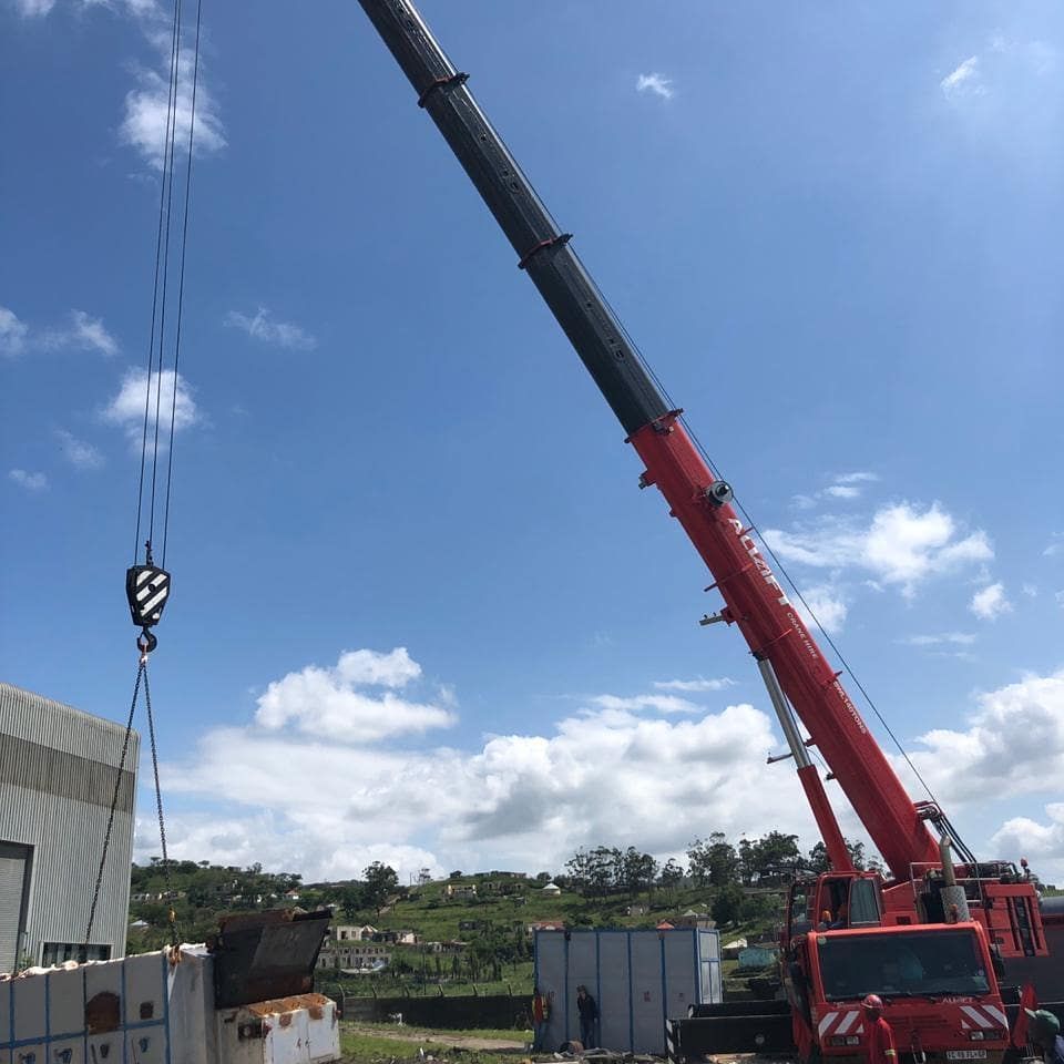 A Large Red Crane Is Lifting A Container In Front Of A Building — All Lift Cranes In Sussex Inlet, NSW