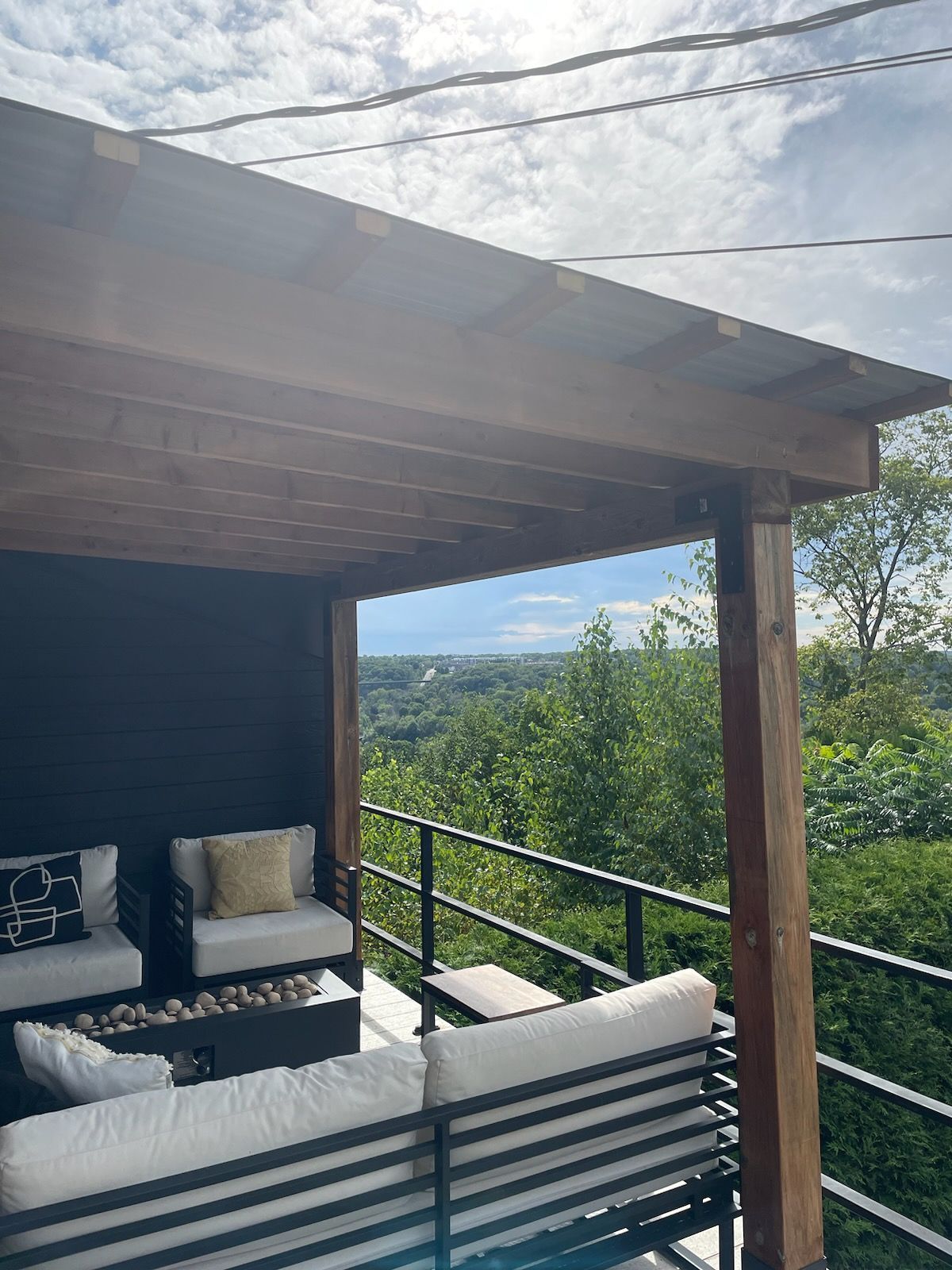 Terrasse couverte avec vue sur une vallée verdoyante sous un ciel lumineux