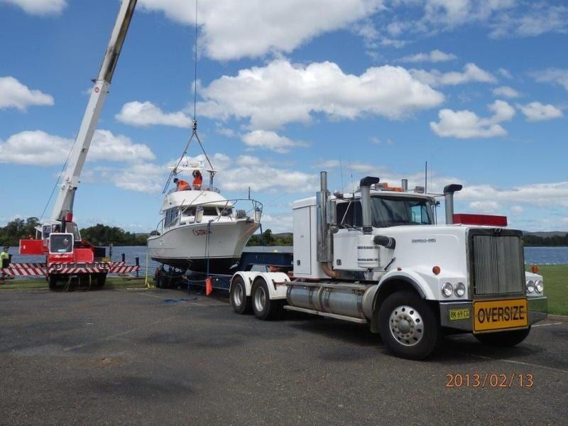 Prime Loader Placing Boat on the Back of Truck Trailer — Elmac Plant Hire In Taree