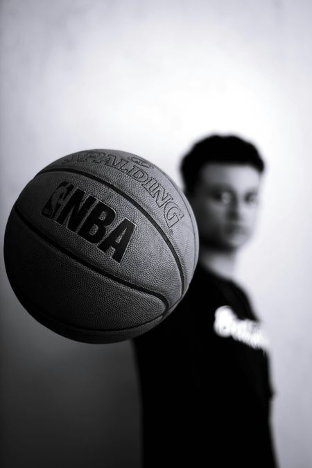 Basketball in focus with a blurred person in the background, black-and-white composition