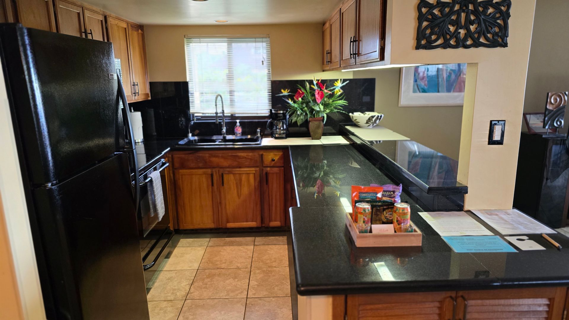 Kitchen with black appliances, dark countertops, and wood cabinets.