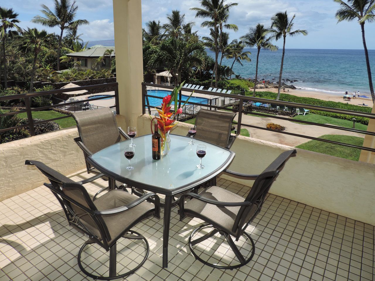 Outdoor patio with table, chairs, flowers, and ocean view.