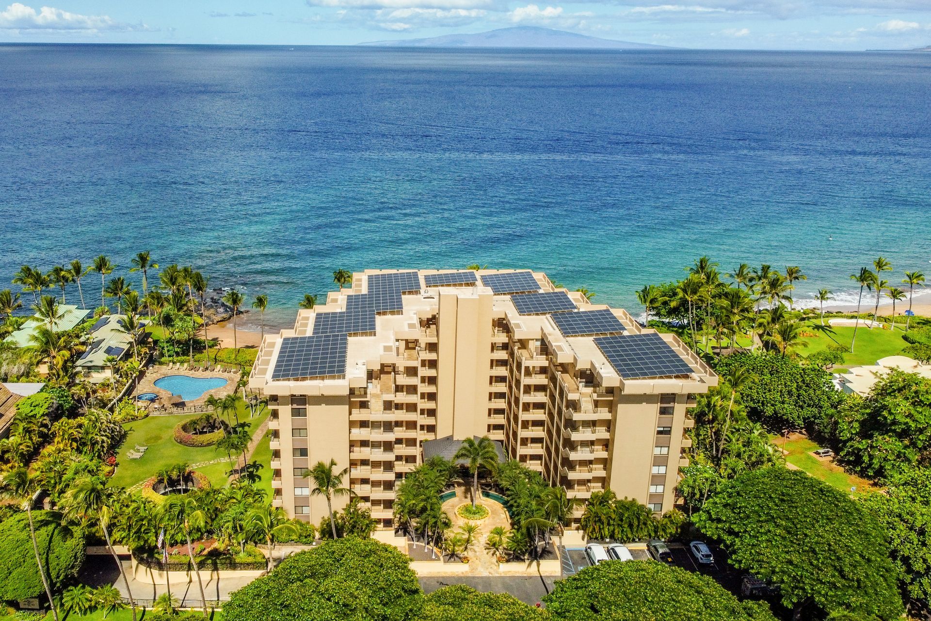 Oceanfront resort building with balconies, surrounded by tropical greenery and turquoise sea views