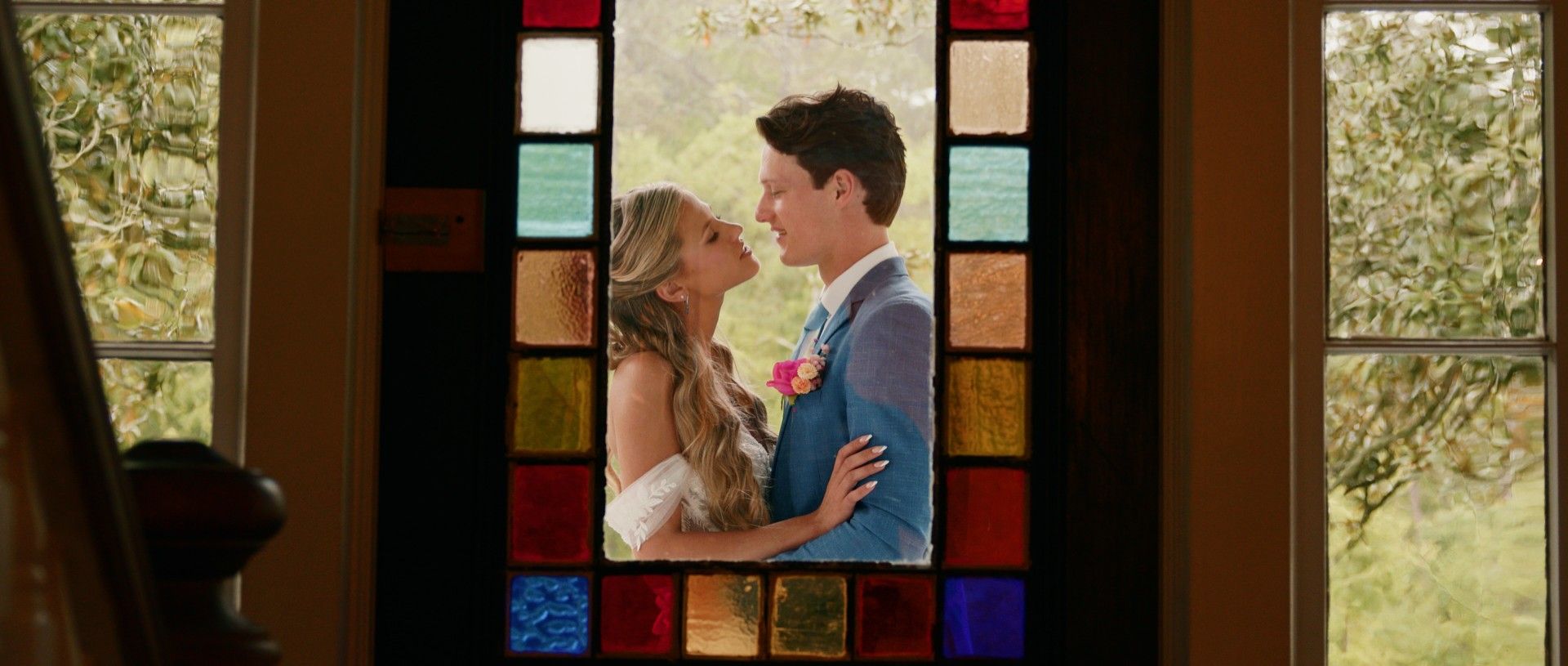 Couple embracing in a wedding photo, seen through a stained glass window.